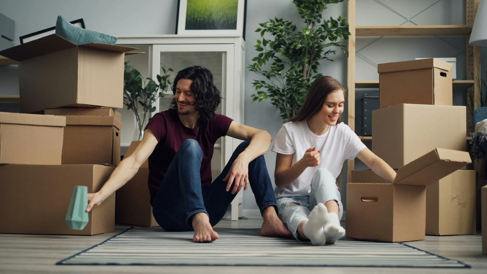 Young couple sitting on the floor surrounded by cardboard boxes in their first home