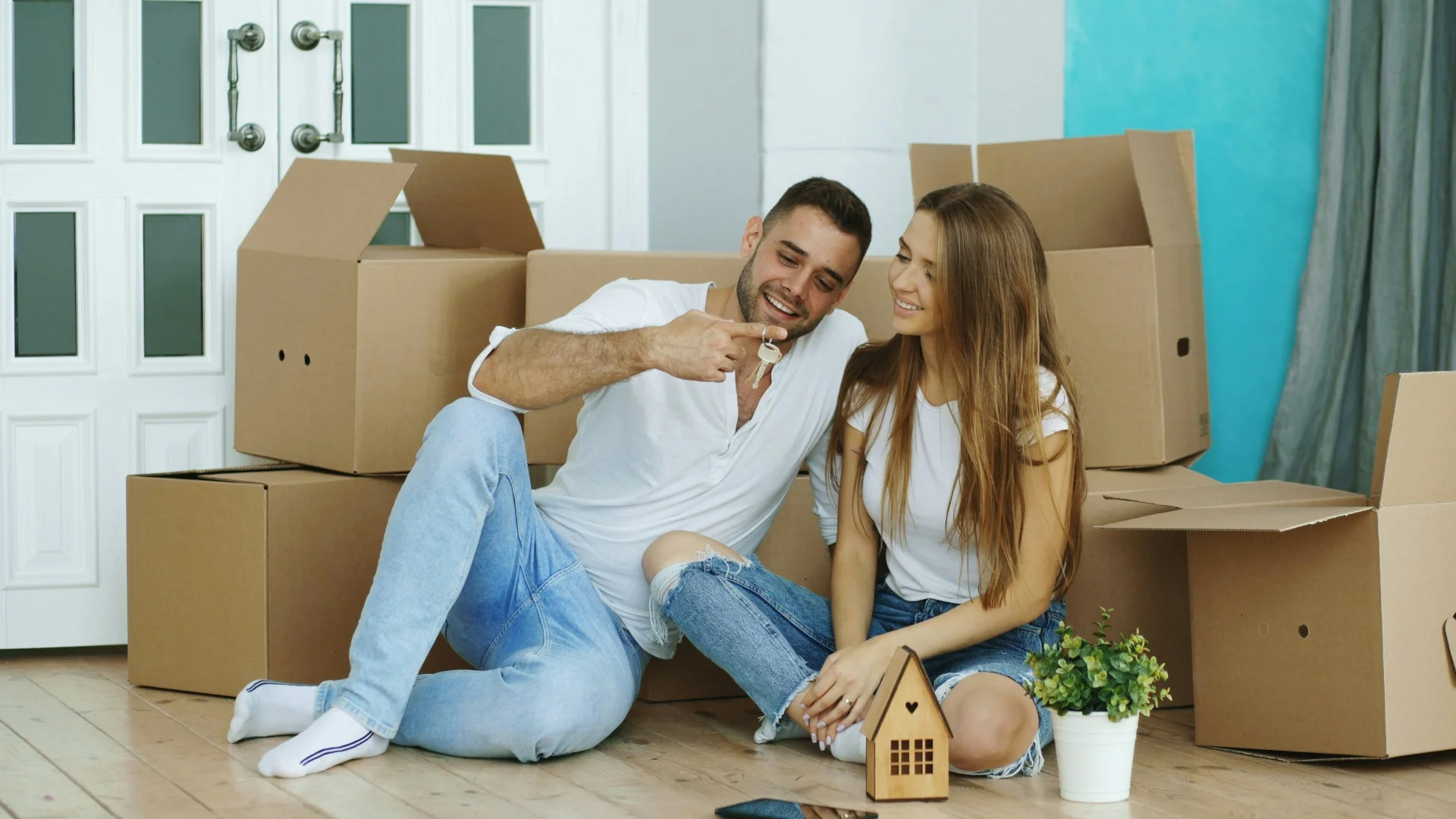 Couple holding keys surrounded by moving boxes in their new home