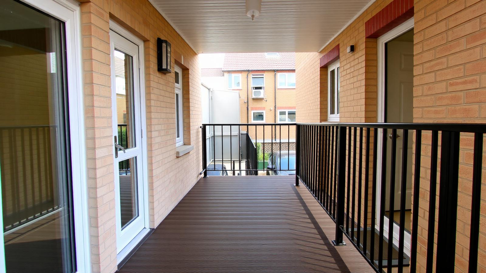 An external deck-access walkway serving front doors on a UK block of flats