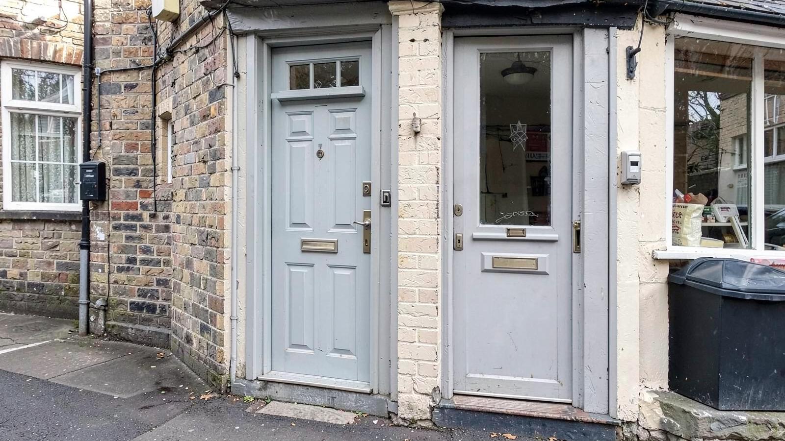 A separate private residential front door next to a shopfront on a British street