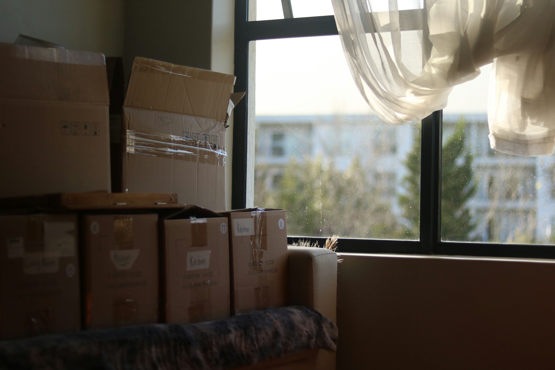 Packing boxes stacked by a window in a home being moved out of